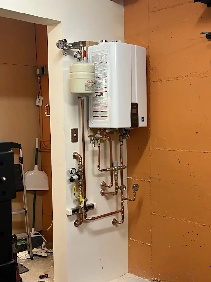 Plumbing technician inspecting water heater connections in McPherson